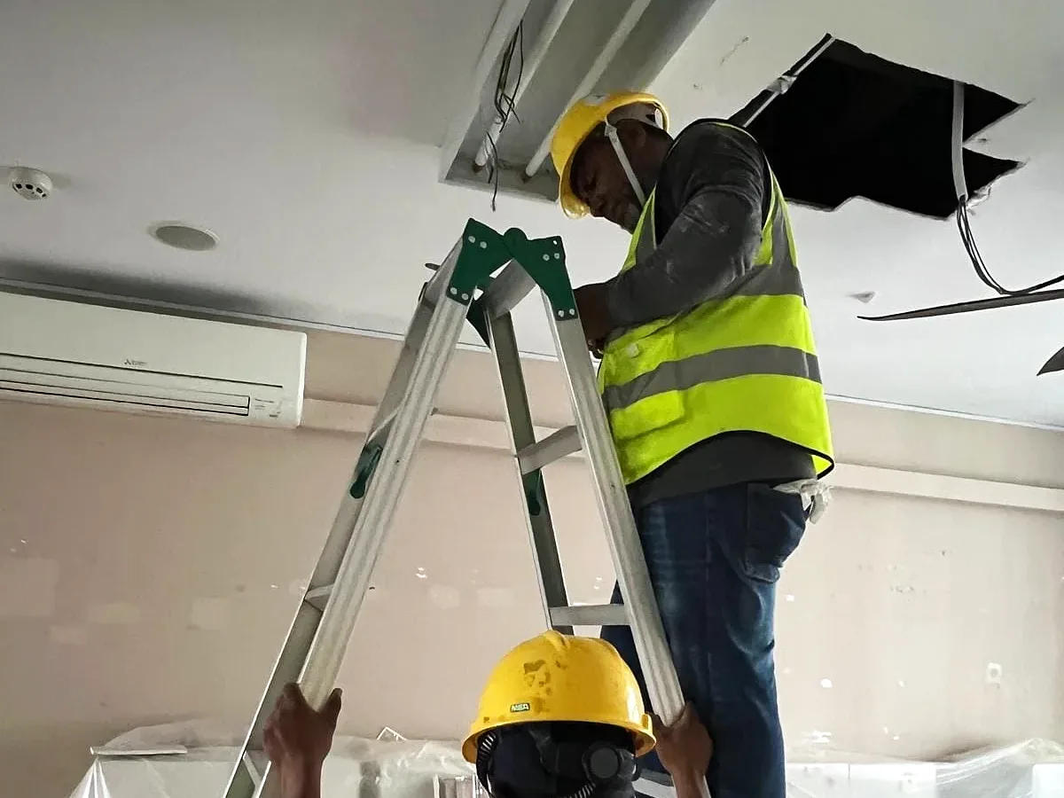 Technicians working at ceiling height on a ladder